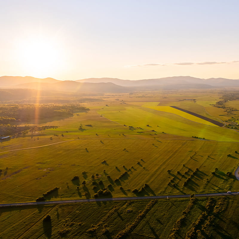 Marketplace & Local Supply Chains drone shot of green field of Krbavsko polje with Velebit mountain in the background during a sunny day