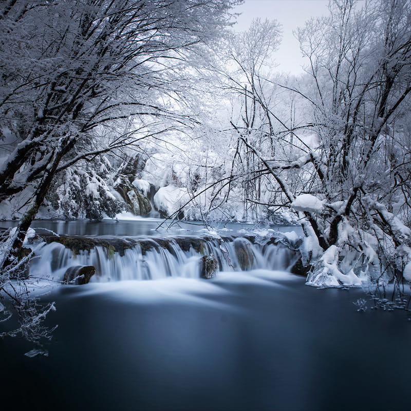 VPR Healing & Movement small waterfall in snow-covered Plitvice lakes national park on a clear winter day